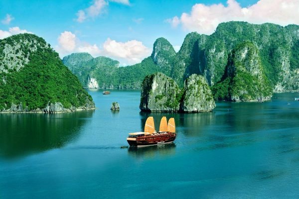 Green limestone karst islands rising out of calm water in Ha Long Bay